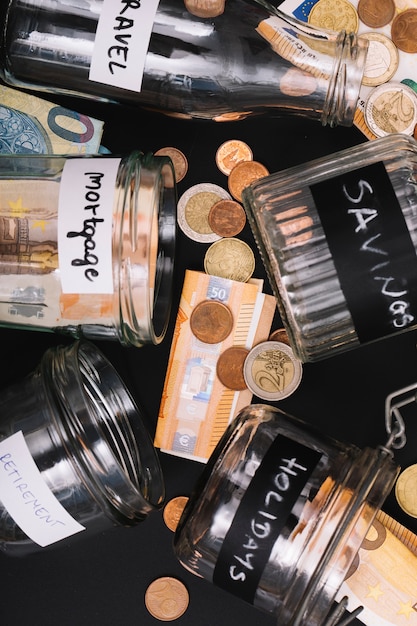 Free photo various open jar with euro currency note and coins on black background