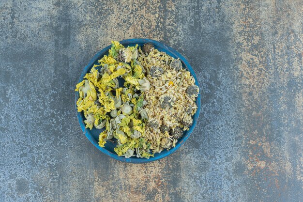 Various organic dry flowers on blue plate.