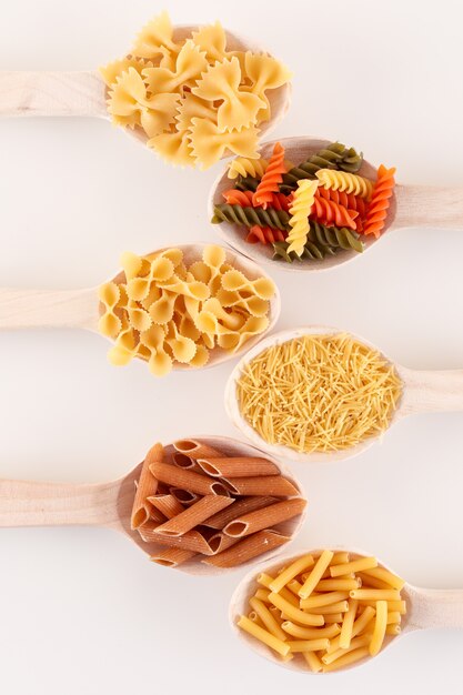 various pasta in spoons on white surface