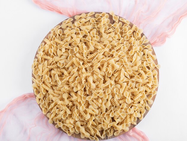 Various pasta on wooden plate with pink cloth.