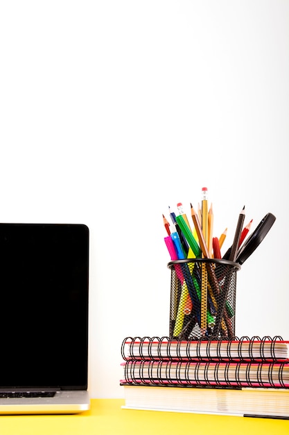 Различные ручки и карандаши в держатель над штабелированной ноутбук возле ноутбука