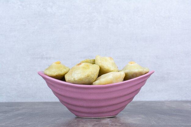 Various pickled fruits in pink bowl.