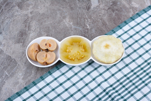 Various pickled vegetables and fruits in bowls with tablecloth.