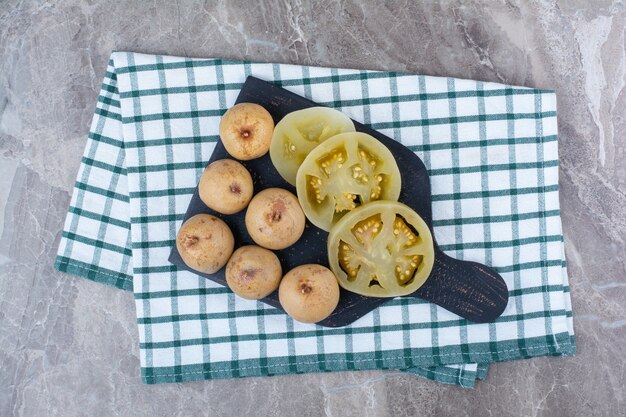 Various pickled vegetables and fruits on dark board.