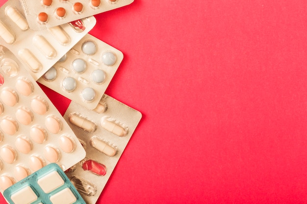 Various pills in blister pack on red background