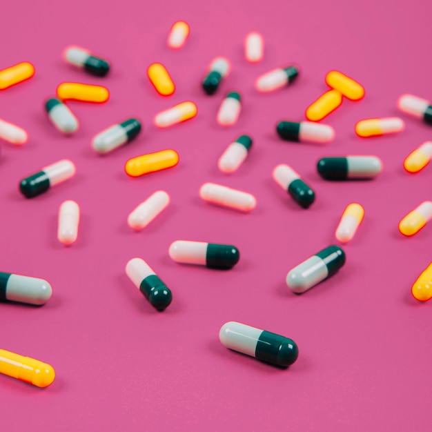 Various pills on pink background