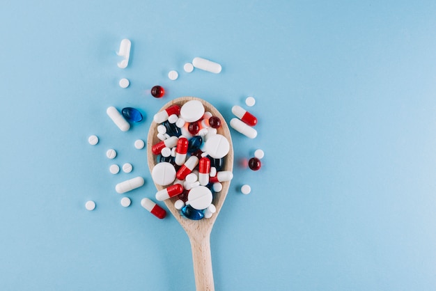 Various pills on wooden spoon