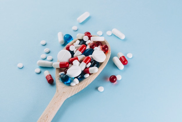 Various pills on wooden spoon