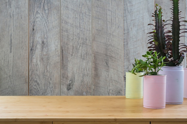 Various plant in the painted recycle cans on wooden table