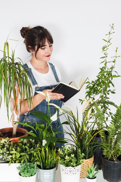 Various potted plants in front of female florist holding diary