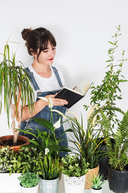 Various potted plants in front of female florist holding diary