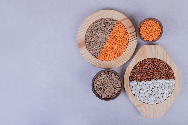 Various raw beans and lentils in wooden bowls.