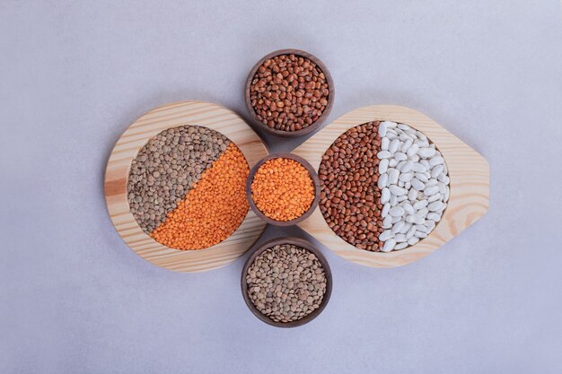 Various raw beans and lentils in wooden bowls.