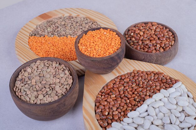 Various raw beans and lentils in wooden bowls.