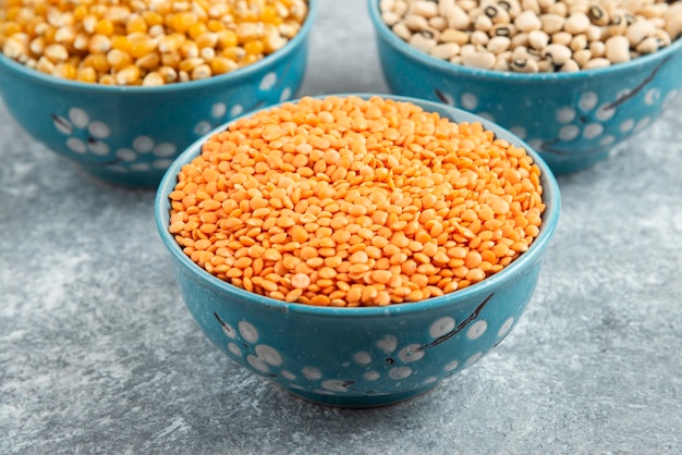 Various raw beans and red lentils on marble table.