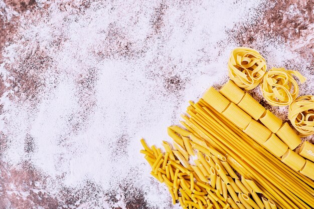 Various raw pastas on wooden table. 