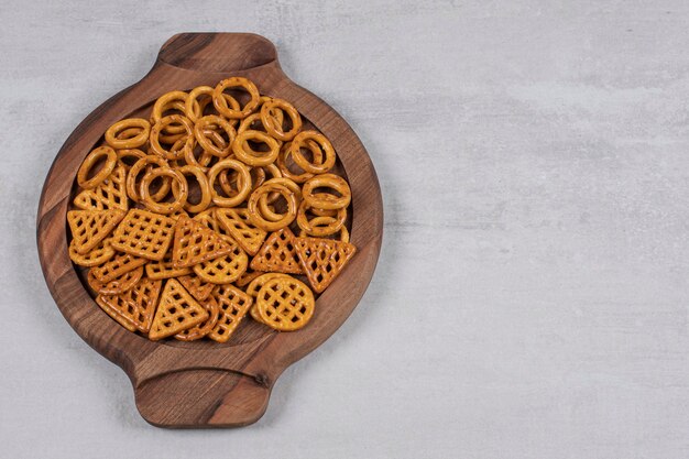 Various salty crackers on wooden board.