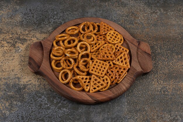 Various salty crackers on wooden board.