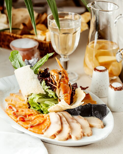 Various seafood on plate with glass of compote