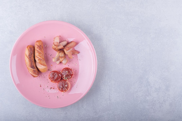 Various shaped fried sausages on pink plate. 