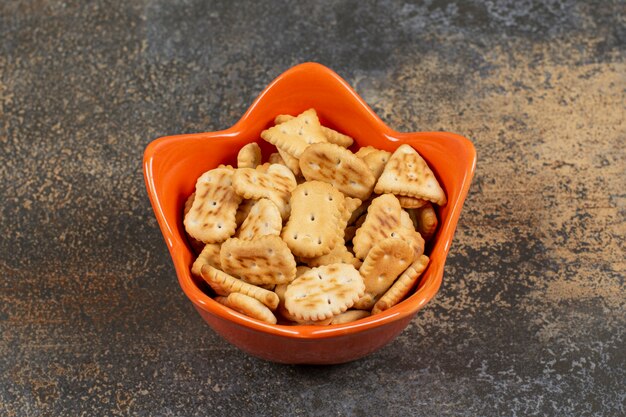 Various shaped salted crackers in orange bowl. 