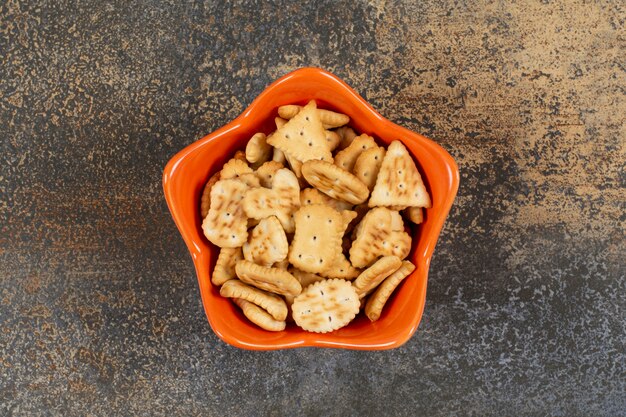 Various shaped salted crackers in orange bowl. 