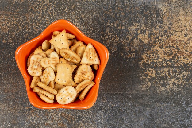 Various shaped salted crackers in orange bowl. 