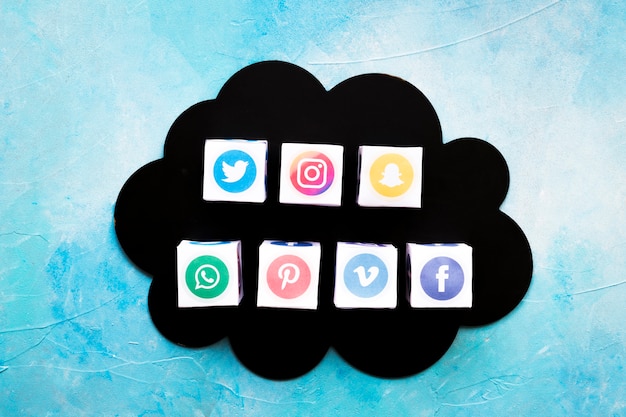 Free photo various social media icons boxes on black cloud over blue background