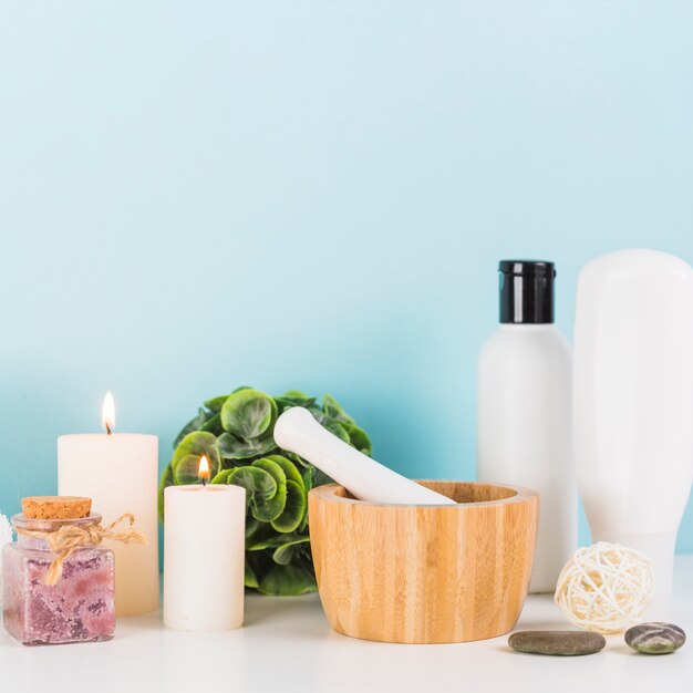 Various spa products with illuminated; candles; mortar and pestle on white tabletop