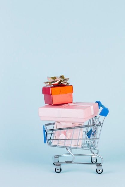 Various stacked parcels in shopping cart on blue backdrop
