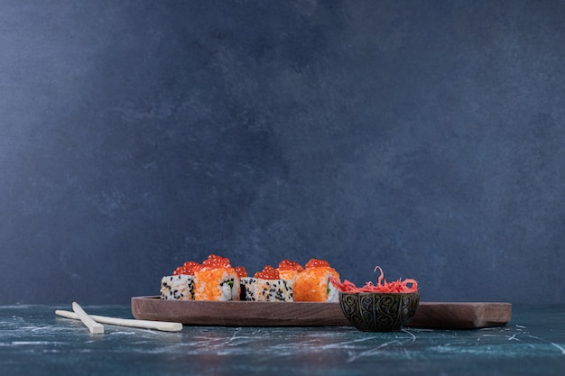 Various sushi rolls decorated with red caviar and chopsticks.