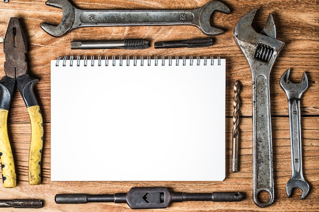 Various tools and the blank notebook on a wooden background