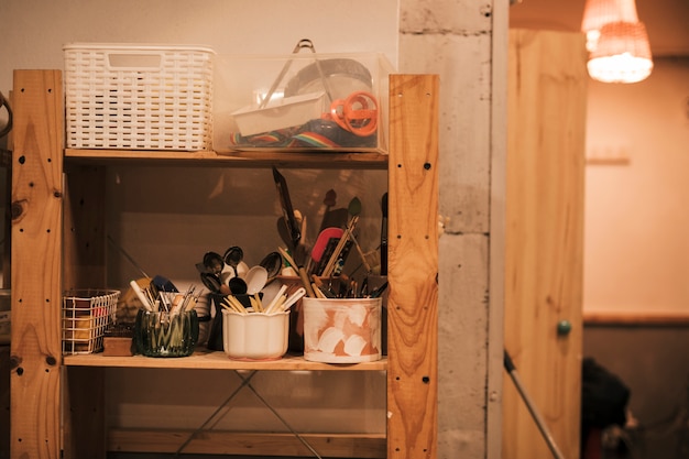 Various tools and spoons on holder in the wooden shelf