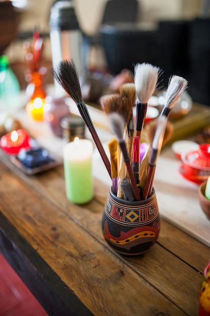 Free photo various type of chinese paint brushes in holder over the wooden table with lighted candles