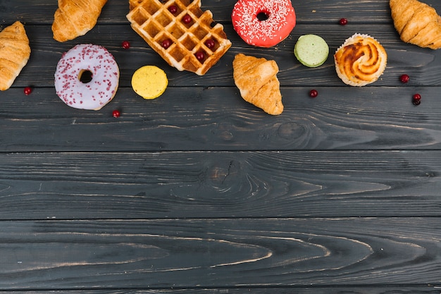 Il vario tipo di dolci ha cotto gli oggetti sulla tavola di legno