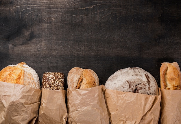 Бесплатное фото Различные виды хлеба, завернутые в бумагу и копией пространства