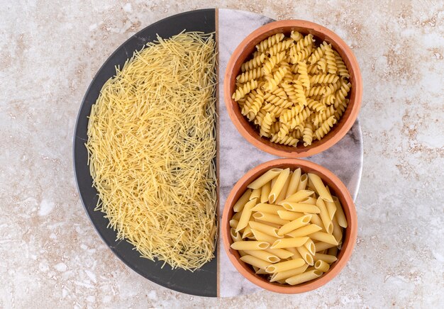 Various types of raw pasta on a marble surface