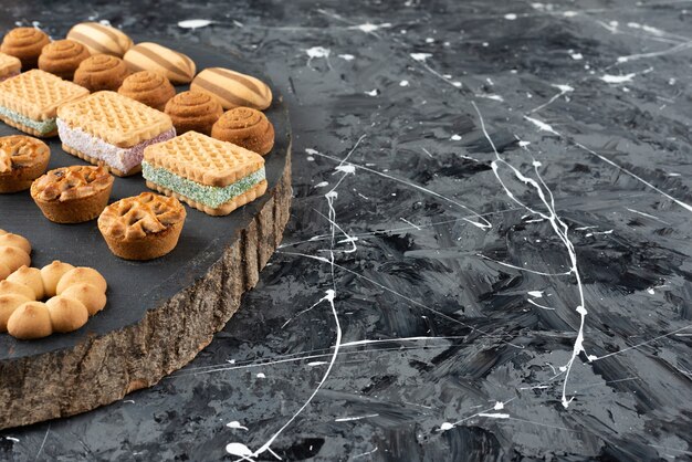 Various types of sweet pastries on a wooden piece . 