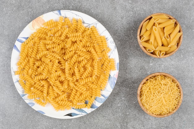 Various uncooked pasta on marble surface