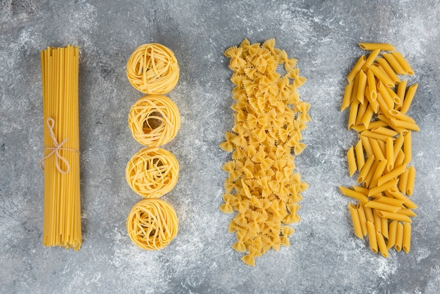 Various uncooked pasta on stone.