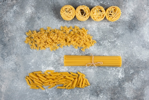 Free photo various uncooked pasta on stone.