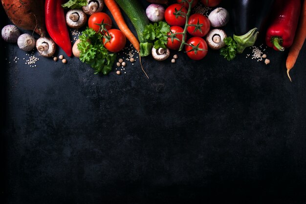 Various vegetables on a black table with space for a message