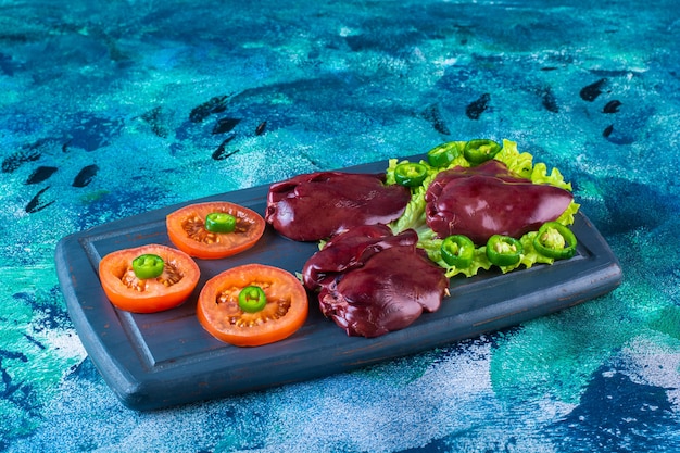 Various vegetables and chicken liver on the wooden tray