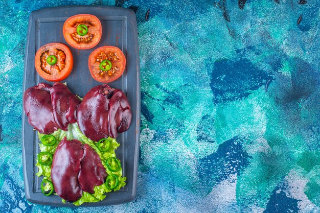 Various vegetables and chicken liver on the wooden tray