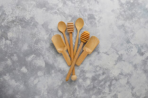 Various wooden spoons with handmade wooden cutting board on grey concrete 