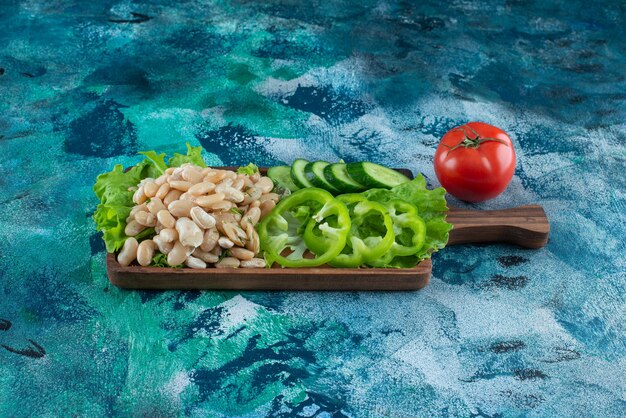 По-разному овощи и бобы на доске на синем столе.