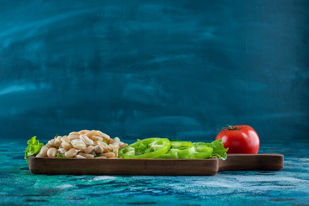 Variously vegetables and beans on a board on the blue table. 