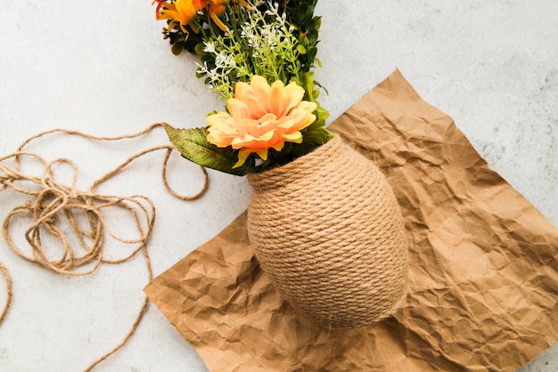 Free photo vase made with string on crumpled brown paper against white backdrop