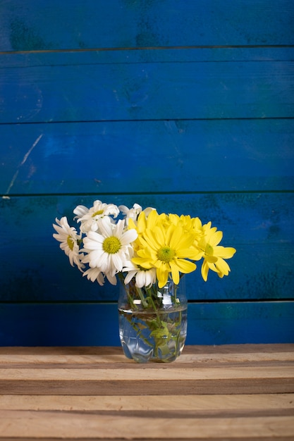 Foto gratuita un vaso di fiori bianchi e gialli