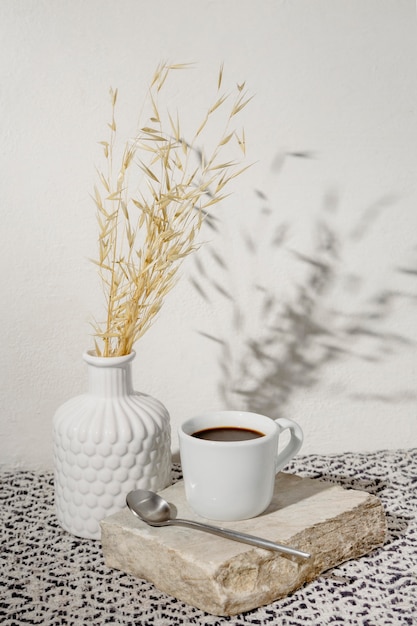 Vase with dry wheat and cup of coffee